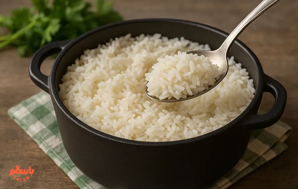 برنج کامفیروزی آبکش شده در قابلمه سیاه رنگ، سرو شده با قاشق روی دستمال چهارخانه