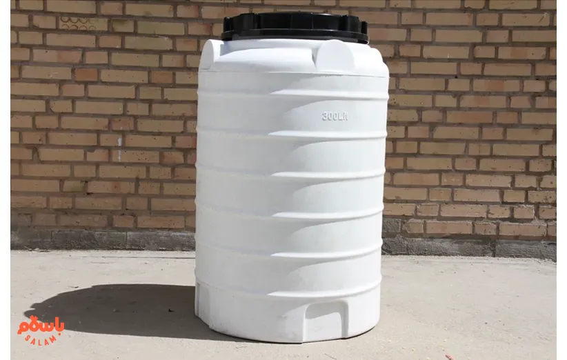 مخزن آب پلاستیکی سفید رنگ با ظرفیت ۳۰۰ لیتر، ایستاده و درب‌دار، مناسب برای مصارف خانگی یا صنعتی، قرار گرفته در فضای باز مقابل دیوار آجری